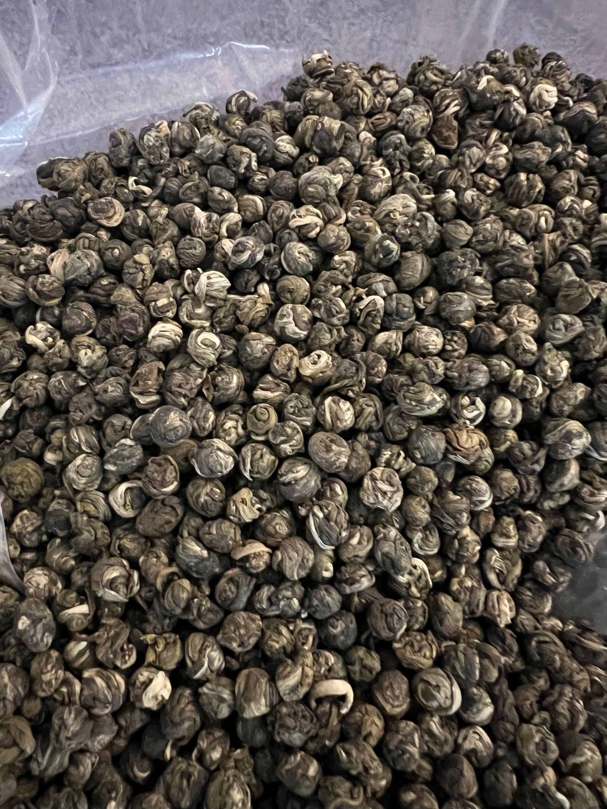 Close-up of Jasmine Dream Tea leaves, showing hand-rolled jasmine pearls infused with fresh jasmine flowers from Fujian, China.”